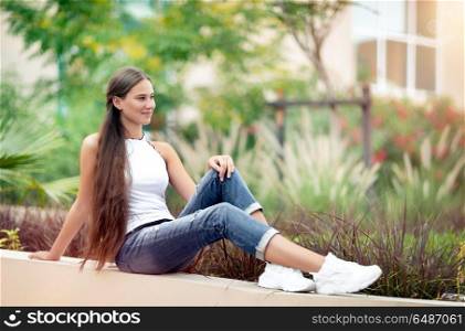 Nice female in the park, beautiful teenage girl sitting outdoors and enjoying freshness of spring nature, with pleasure spending peaceful weekend outside the city. Nice female in the spring park