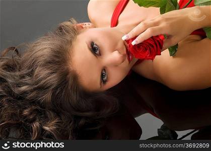 nice girl laying on black with a red rose near her face