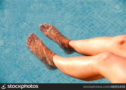 Nice legs of woman soaking feet in swimming pool