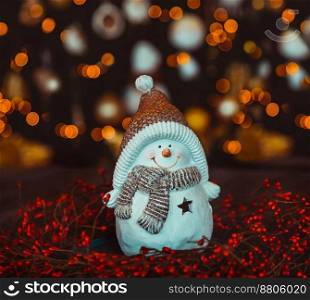 Nice Little Snowman Candlestick on the Table over Decorated Glowing Christmas Tree Bokeh Lights Background. Happy Winter Holidays at Home. Merry Christmas and Happy New Year 