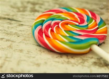 Nice lollipop with many colors in a spiral on a wooden background