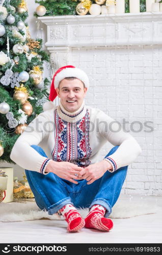nice man in a sweater and New Year&rsquo;s socks sitting near a Christmas tree