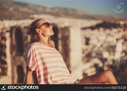 Nice peaceful girl sitting on the high point and enjoying beautiful amazing view on an ancient city in Greece. Happy travel to Europe.. Beautiful Woman in Greece summer vacation