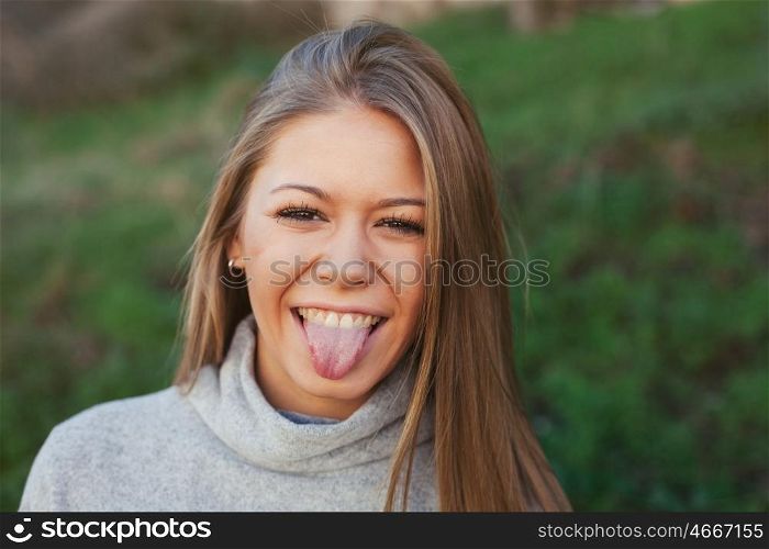 Nice portrait of blonde girl showing the tongue with green grass of background