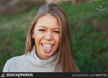 Nice portrait of blonde girl showing the tongue with green grass of background