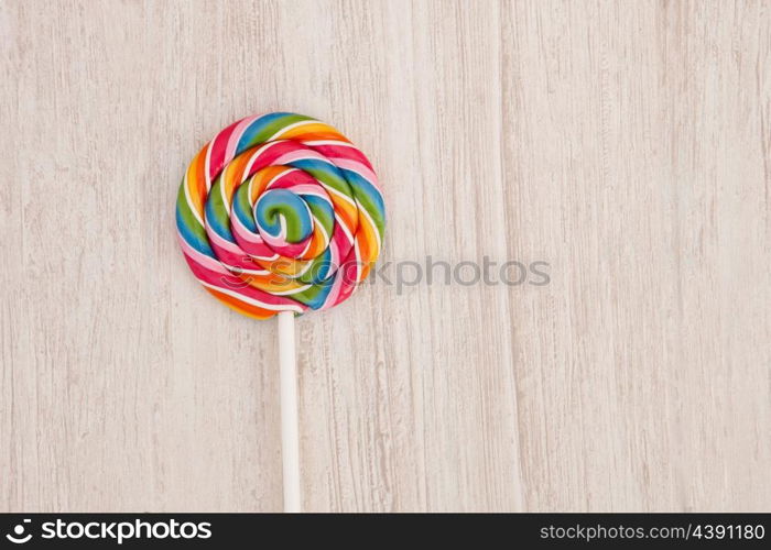 Nice round lollipop with many colors in a spiral on a wooden background