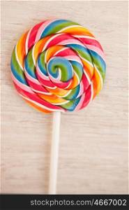Nice round lollipop with many colors in a spiral on a wooden background