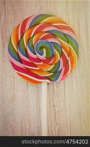 Nice round lollipop with many colors in a spiral on a wooden background