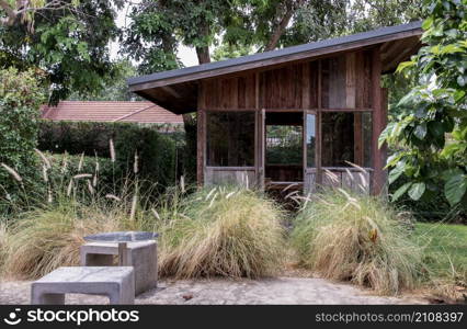 Nice small wooden hut. Green garden joy in summer with Stone benchs and perennial ryegrass plant. Relax in the garden and enjoy the beautiful weather. Selective focus.