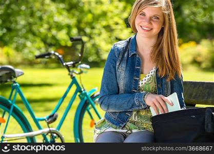 Nice student girl sitting in the park with bike