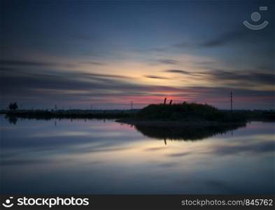 Nice sunset above a small lake with an island near the Dutch village Sliedrecht. Sunset near Sliedrecht