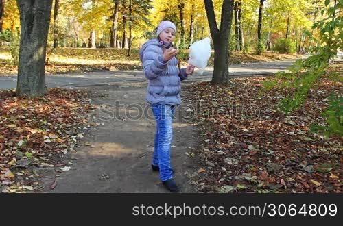 nice teen girl pecks off pieces cotton candy and eats in beautiful autumn city park