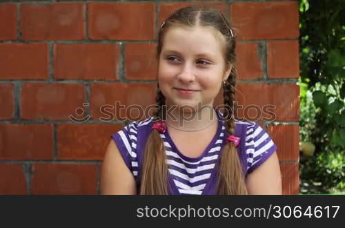 nice teen girl sits in front of brick wall and laughs