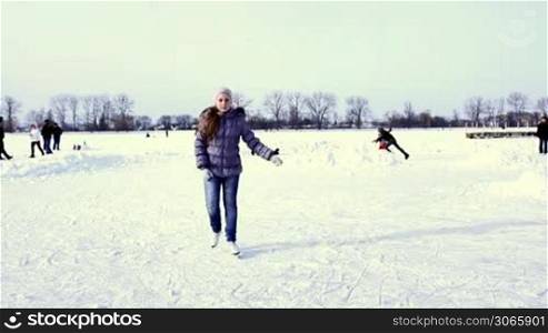 nice teenage girl quickly goes skating by winter frozen lake to camera
