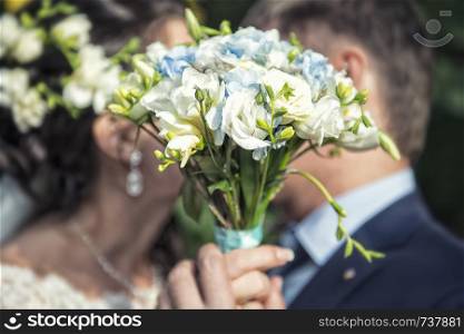 nice wedding bouquet in bride's hand. Kiss across bouquet. nice wedding bouquet in bride's hand