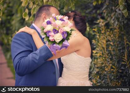 nice wedding bouquet in bride's hand. Kiss across bouquet. nice wedding bouquet in bride's hand