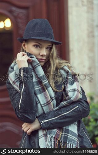 nice woman , covering her face with a scarf , she has freckles , posing near an old fashion house door.
