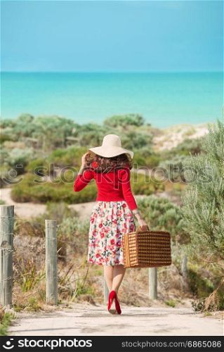 Nice Woman traveler in retro style dress walking through dunes to the beach