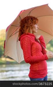 nice woman with umbrella looking thoughtful the river