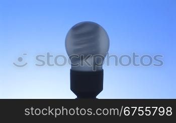 nicht leuchtende Energiesparlampe vor blauem Hintergrund