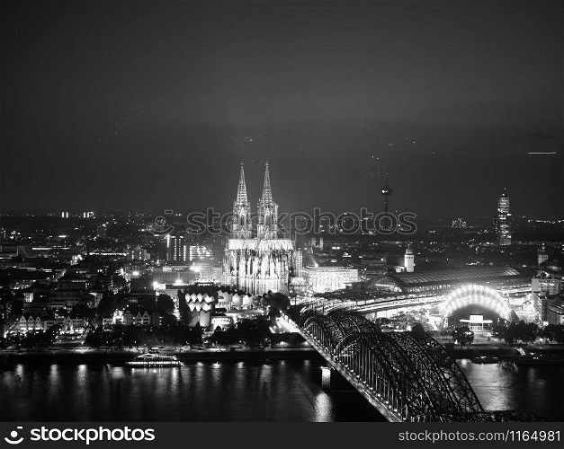 Night aerial view Koelner Dom Sankt Petrus (meaning St Peter Cathedral) gothic church and Hohenzollernbruecke (meaning Hohenzollern Bridge) crossing the river Rhein in Koeln, Germany in black and white. Aerial night view of St Peter Cathedral and Hohenzollern Bridge, black and white