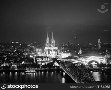 Night aerial view Koelner Dom Sankt Petrus (meaning St Peter Cathedral) gothic church and Hohenzollernbruecke (meaning Hohenzollern Bridge) crossing the river Rhein in Koeln, Germany in black and white. Aerial night view of St Peter Cathedral and Hohenzollern Bridge, black and white