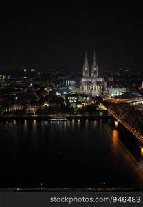 Night aerial view Koelner Dom Sankt Petrus (meaning St Peter Cathedral) gothic church and Hohenzollernbruecke (meaning Hohenzollern Bridge) crossing the river Rhein in Koeln, Germany. Aerial night view of St Peter Cathedral and Hohenzollern Bridge over river Rhine in Koeln
