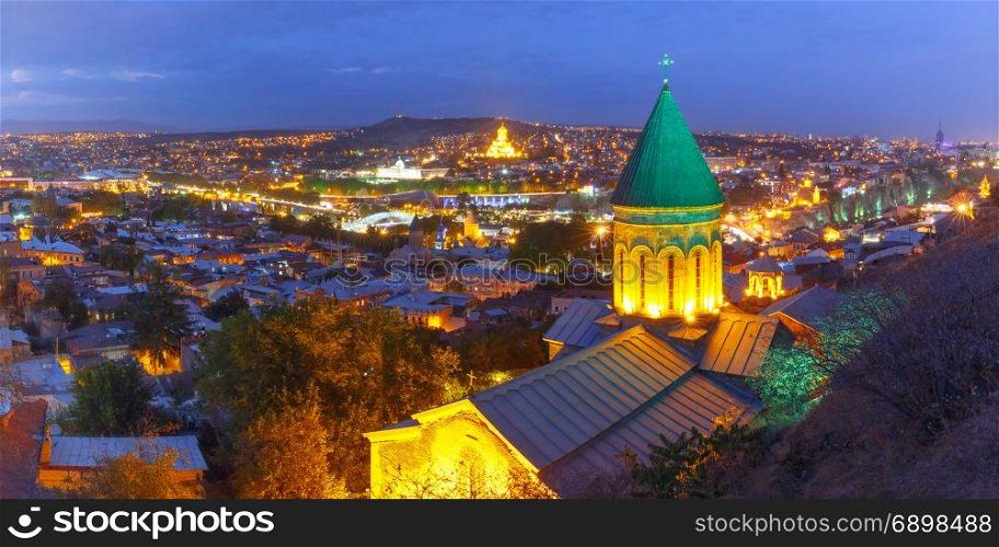 Night aerial view of Old Town, Tbilisi, Georgia. Aerial panoramic view of Old Town with dome of Lower Bethlemi Church and Sameba Holy Trinity Cathedral, Metekhi Church, bridge of Peace and Presidential Palace during evening blue hour, Tbilisi, Georgia