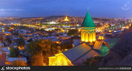 Night aerial view of Old Town, Tbilisi, Georgia. Aerial panoramic view of Old Town with dome of Lower Bethlemi Church and Sameba Holy Trinity Cathedral, Metekhi Church, bridge of Peace and Presidential Palace during evening blue hour, Tbilisi, Georgia