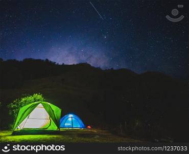 night camping concept from tents on mountain under night sky with stars and milky way.