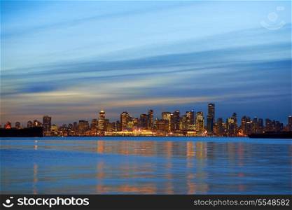 Night city, panoramic scene of downtown reflected in blue water. Vancouver, Canada
