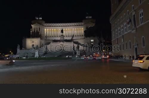 Night city traffic by Altar of Fatherland in Rome at night. Woman with tablet computer making shot of Italian landmark. Tourism in Europe