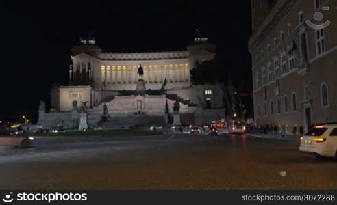 Night city traffic by Altar of Fatherland in Rome at night. Woman with tablet computer making shot of Italian landmark. Tourism in Europe