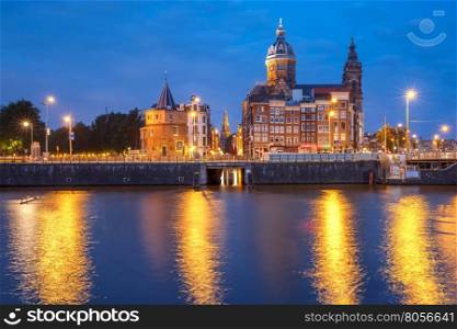Night city view of Amsterdam canal and Basilica of Saint Nicholas, Schreierstoren or Weepers Tower and Oude Kerk, Holland, Netherlands.
