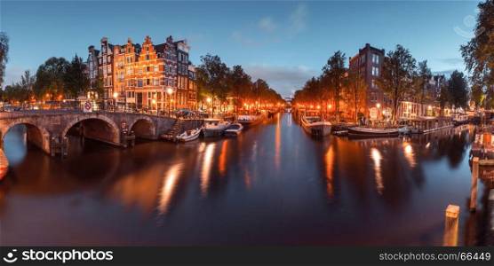 Night city view of Amsterdam canal and bridge. Panorama of Amsterdam canal, bridge and typical houses, boats and bicycles during evening twilight blue hour, Holland, Netherlands. Used toning