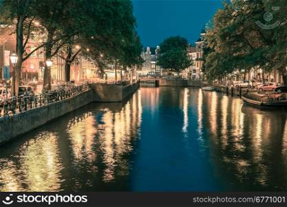 Night city view of Amsterdam canal and bridge, boats and bicycles, Holland, Netherlands.. Toning in cool tones