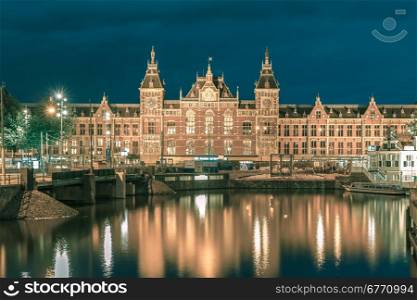 Night city view of Amsterdam canal and Centraal Station, Holland, Netherlands. Long exposure.. Toning in cool tones