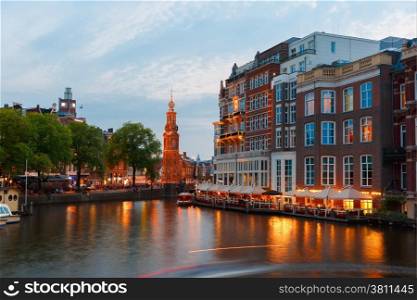 Night city view of Amsterdam canal, bridge and Munttoren tower, Holland, Netherlands.