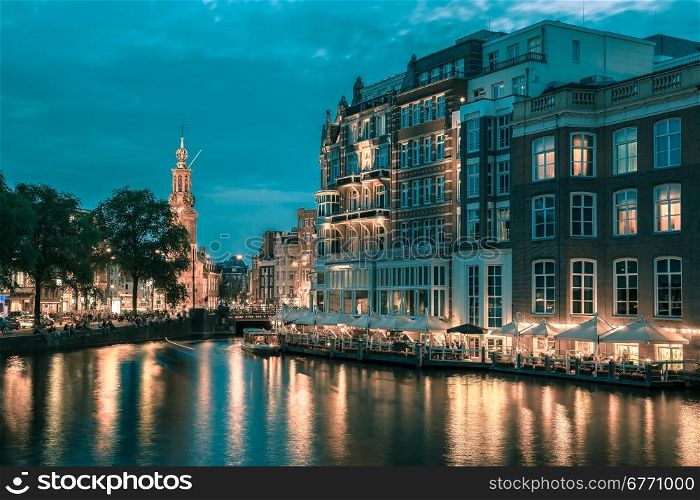 Night city view of Amsterdam canal, bridge and Munttoren tower, Holland, Netherlands.. Toning in cool tones