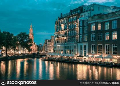 Night city view of Amsterdam canal, bridge and Munttoren tower, Holland, Netherlands.. Toning in cool tones