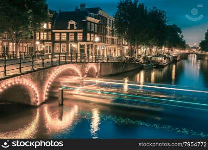 Night city view of Amsterdam canal, bridge and typical houses, boats and bicycles, Holland, Netherlands.. Toning in cool tones
