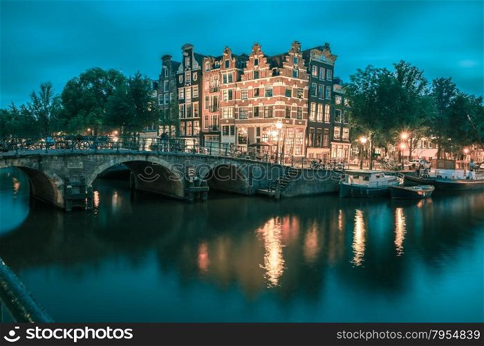 Night city view of Amsterdam canal, bridge and typical houses, boats and bicycles, Holland, Netherlands... Toning in cool tones