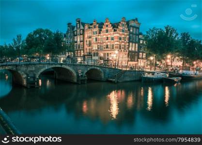 Night city view of Amsterdam canal, bridge and typical houses, boats and bicycles, Holland, Netherlands... Toning in cool tones