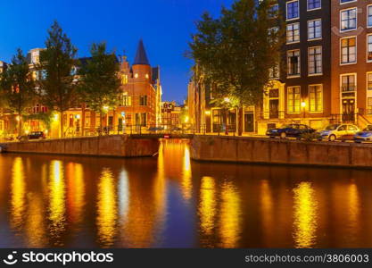 Night city view of Amsterdam canal, bridge and typical houses, Holland, Netherlands.