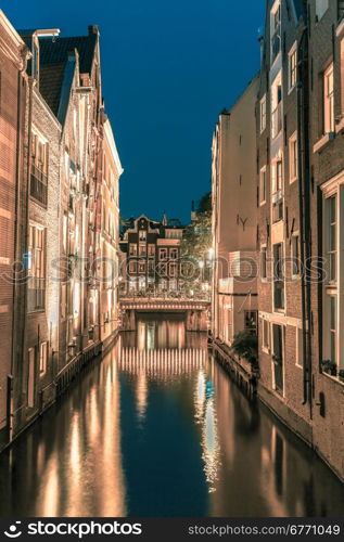 Night city view of Amsterdam canal, bridge, typical houses and bicycles, Holland, Netherlands.. Toning in cool tones