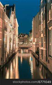 Night city view of Amsterdam canal, bridge, typical houses and bicycles, Holland, Netherlands.. Toning in cool tones