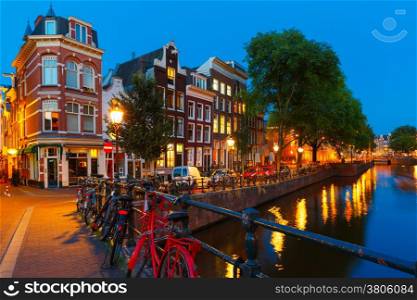 Night city view of Amsterdam canal, bridge with typical houses and bicycles, Holland, Netherlands.