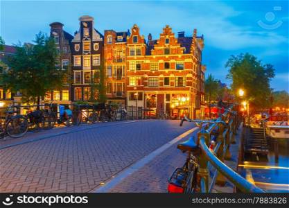 Night city view of Amsterdam canal, bridge with typical houses and bicycles, Holland, Netherlands.
