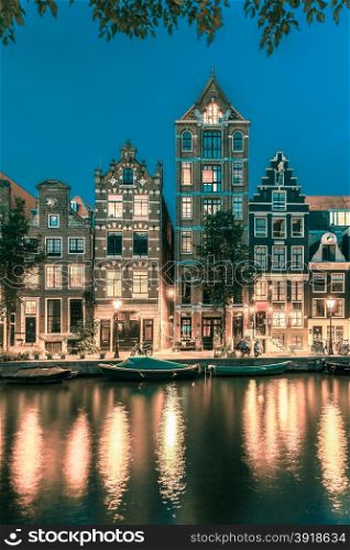 Night city view of Amsterdam canal Herengracht, typical dutch houses and boats, Holland, Netherlands.. Toning in cool tones
