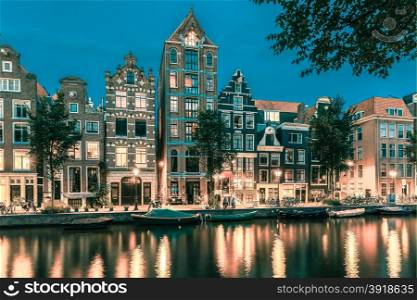 Night city view of Amsterdam canal Herengracht, typical dutch houses and boats, Holland, Netherlands.. Toning in cool tones
